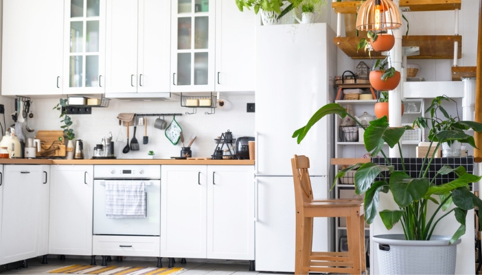 A bright, white kitchen with a vintage inspired white fridge and range. Lots of greenery.