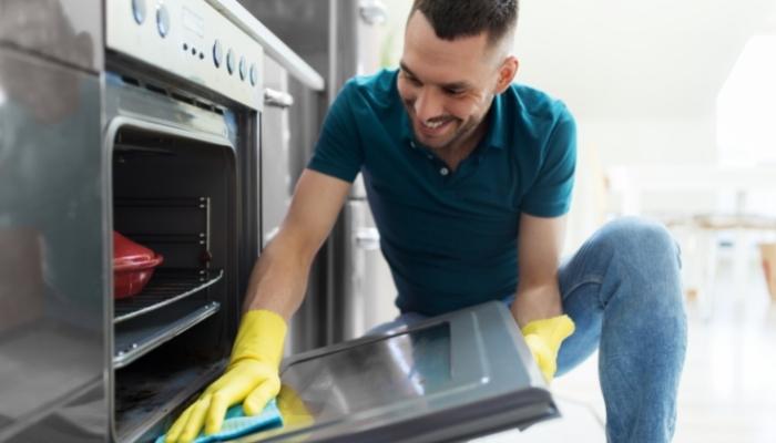 Man wiping down the oven with a sponge