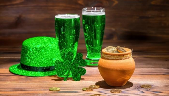 Leprechaun hat, two green drinks, and a pot of gold on a table