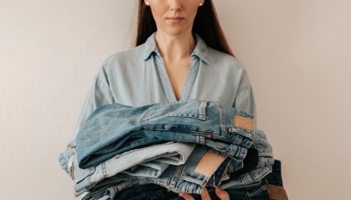 Woman holding a pile of denim jeans