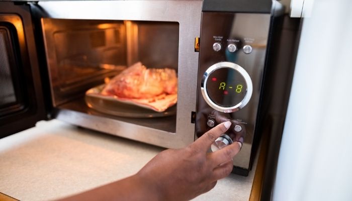 hand starting the microwave oven to cook food