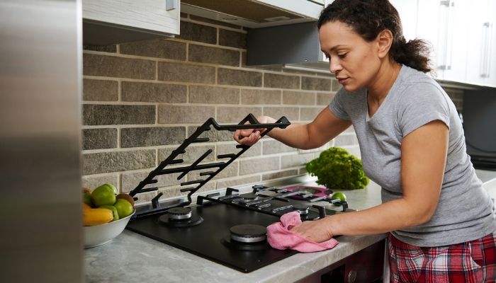 woman wiping off gas cooktop