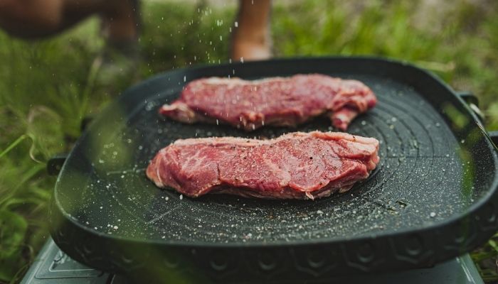 steaks cooking on portable cooktop