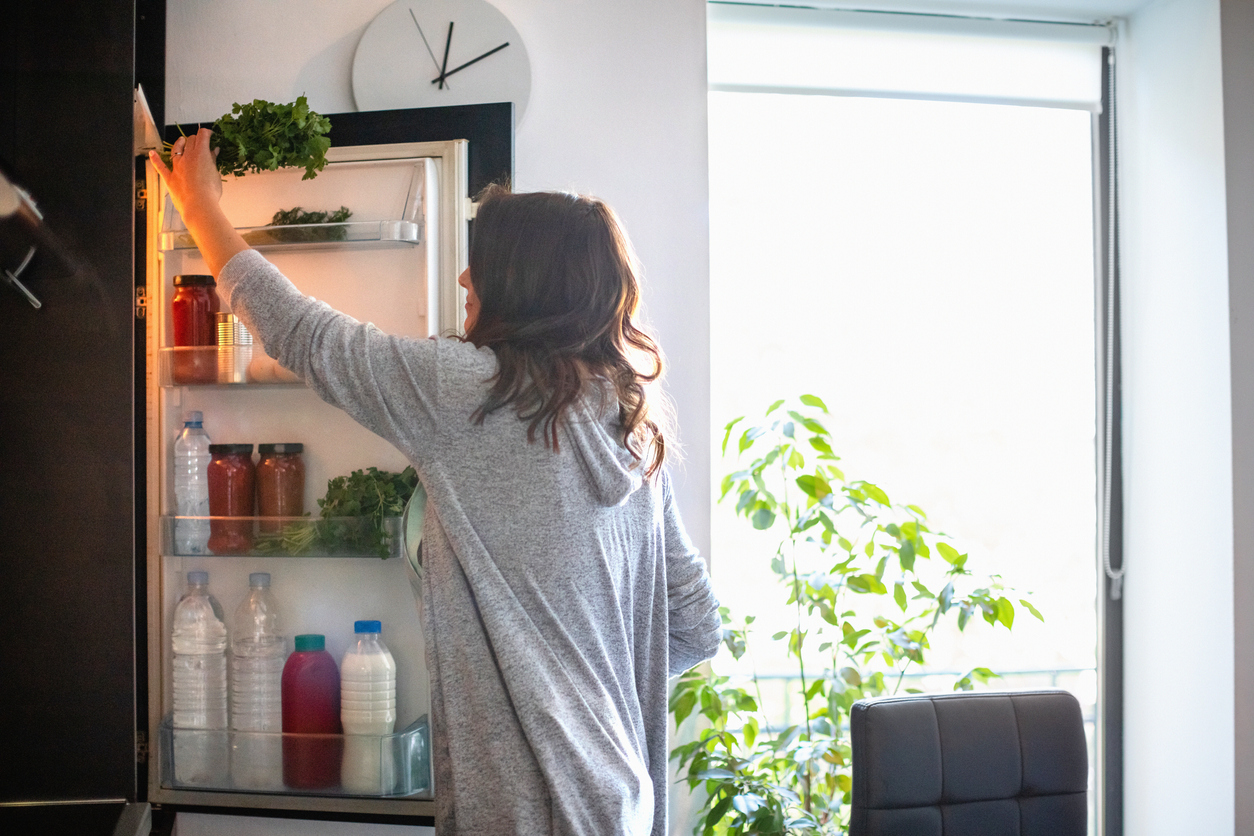 woman reaching into a fridge