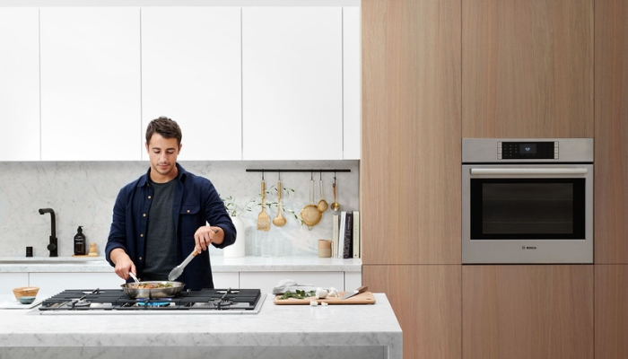 A man cooks dinner on his cooktop in a modern kitchen