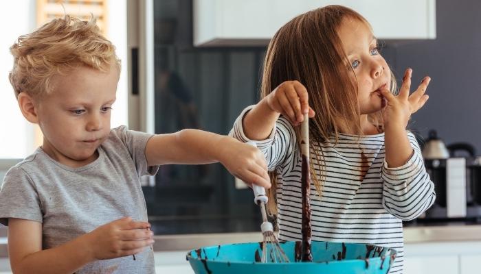Two kids eating chocolate batter