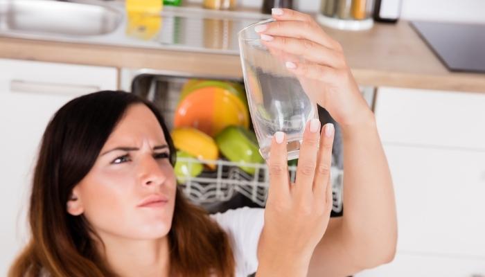Woman studying clean glass as if it’s still dirty