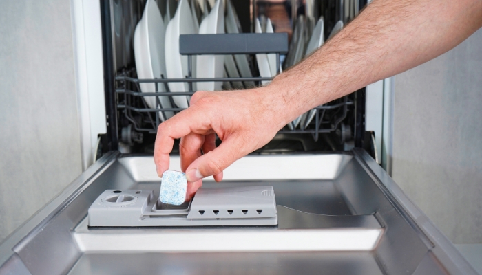 Closeup of someone adding a dishwasher tablet