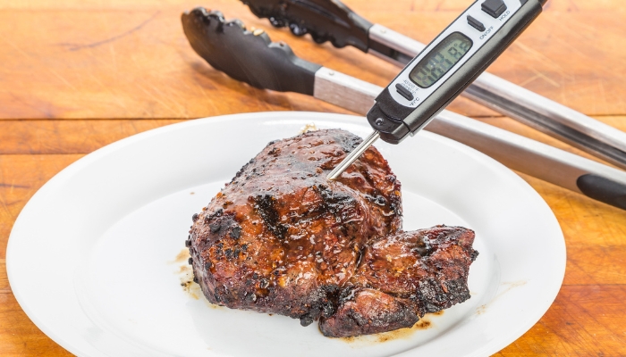 BBQ meat with a meat thermometer indicating how hot it is