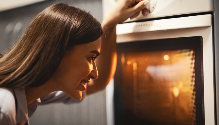 Woman checking the oven using the oven light