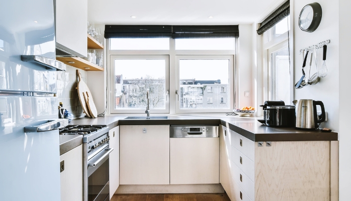 A small apartment kitchen is brightly lit by a window.