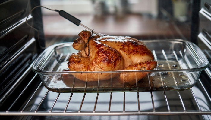 Closeup of integrated temperature probe inside a cooking chicken in the oven