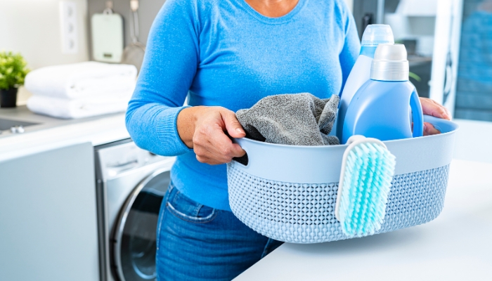 Closeup of someone holding basket of laundry with a bottle of fabric softener