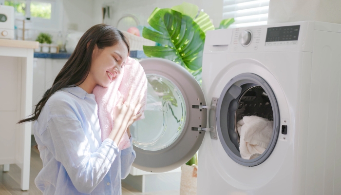 Woman pulling warm and soft blanket out of the dryer