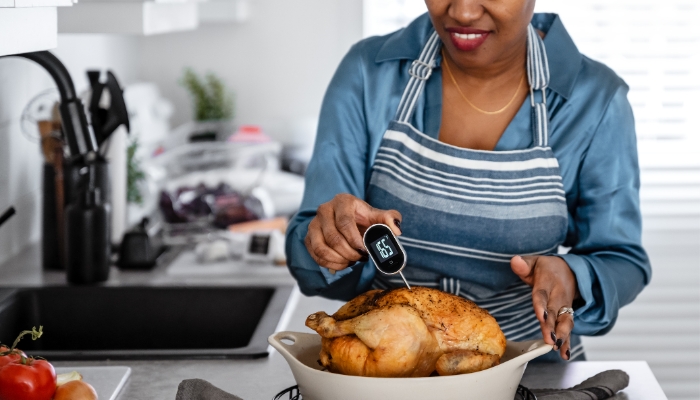 Woman inserting a digital meat thermometer into her cooked chicken
