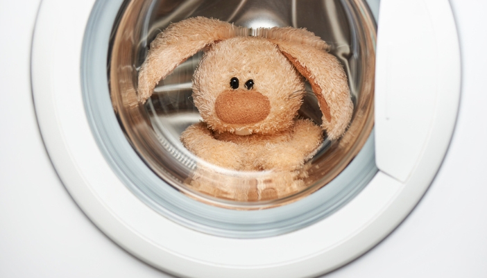 A stuffed rabbit sits in a white dryer.