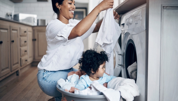 A woman and her daughter empty a white dryer happily.