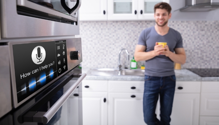 A man stands in a clean kitchen and talks to his smart oven assistant.