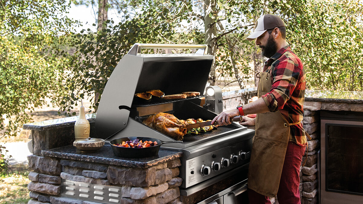 Man cooking on a DCS grill outdoors 