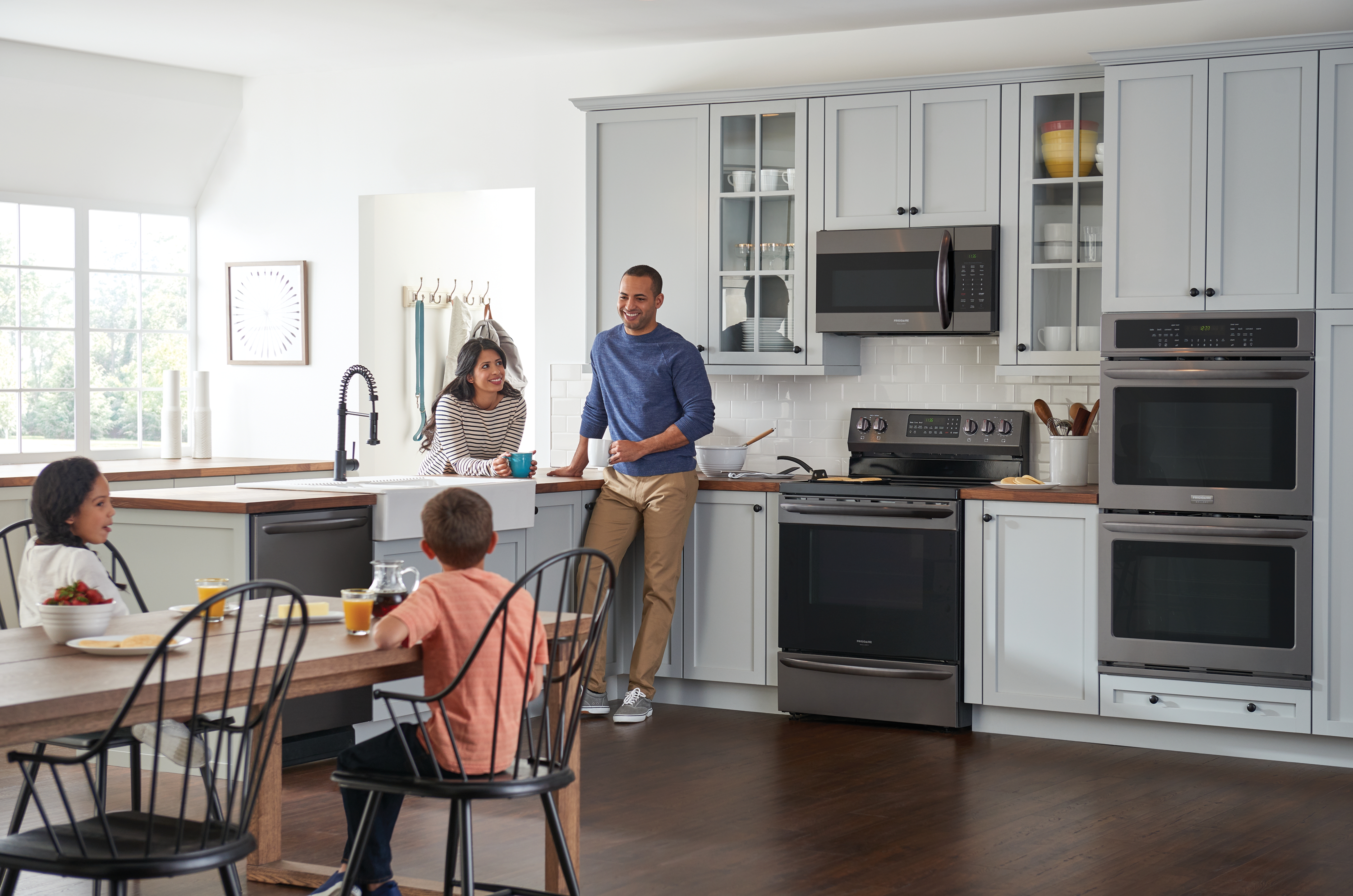 A family gathers in their kitchen which includes Electrolux appliances