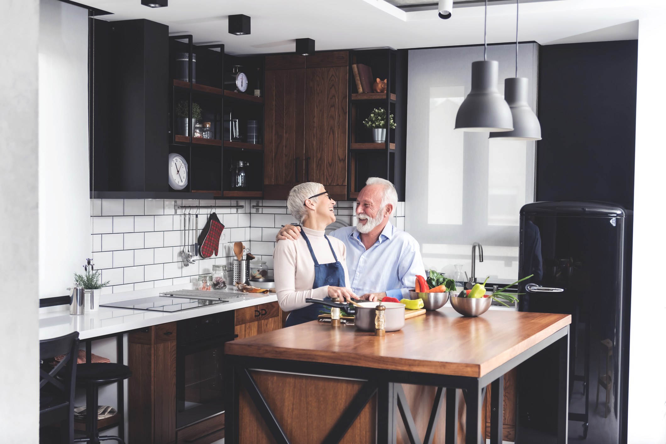 elderly couple cooking and laughing together in the kitchen
