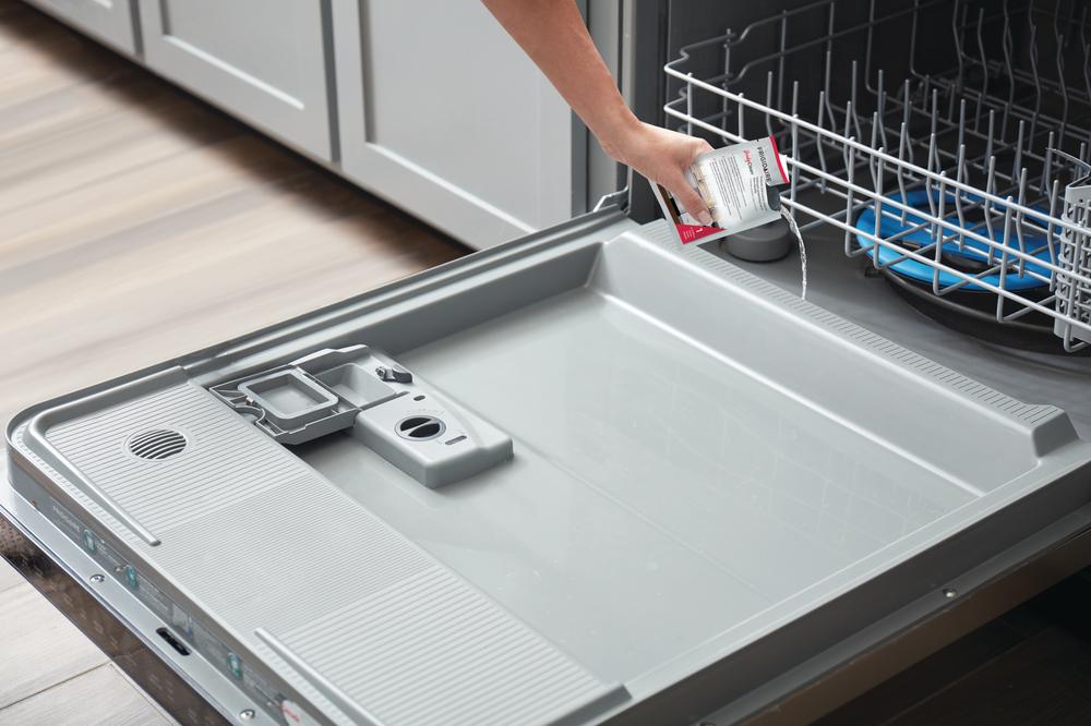  female hand pours probiotic cleaner to maintain her dishwasher