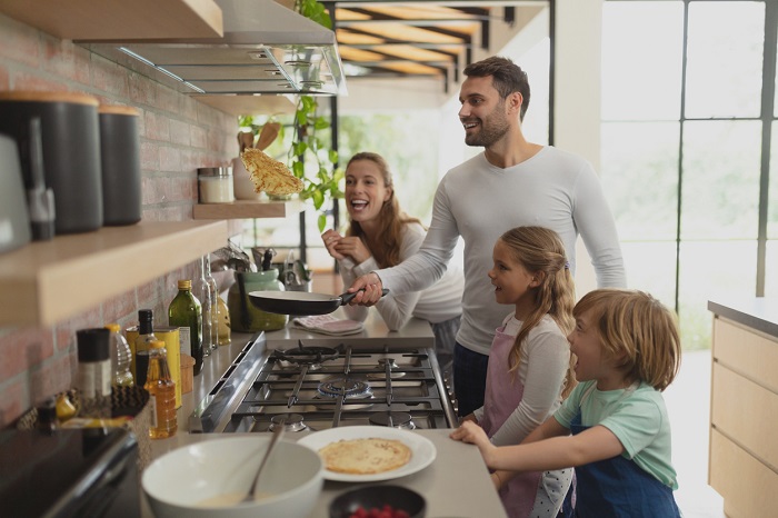 Family having fun cooking in kitchen with gas range