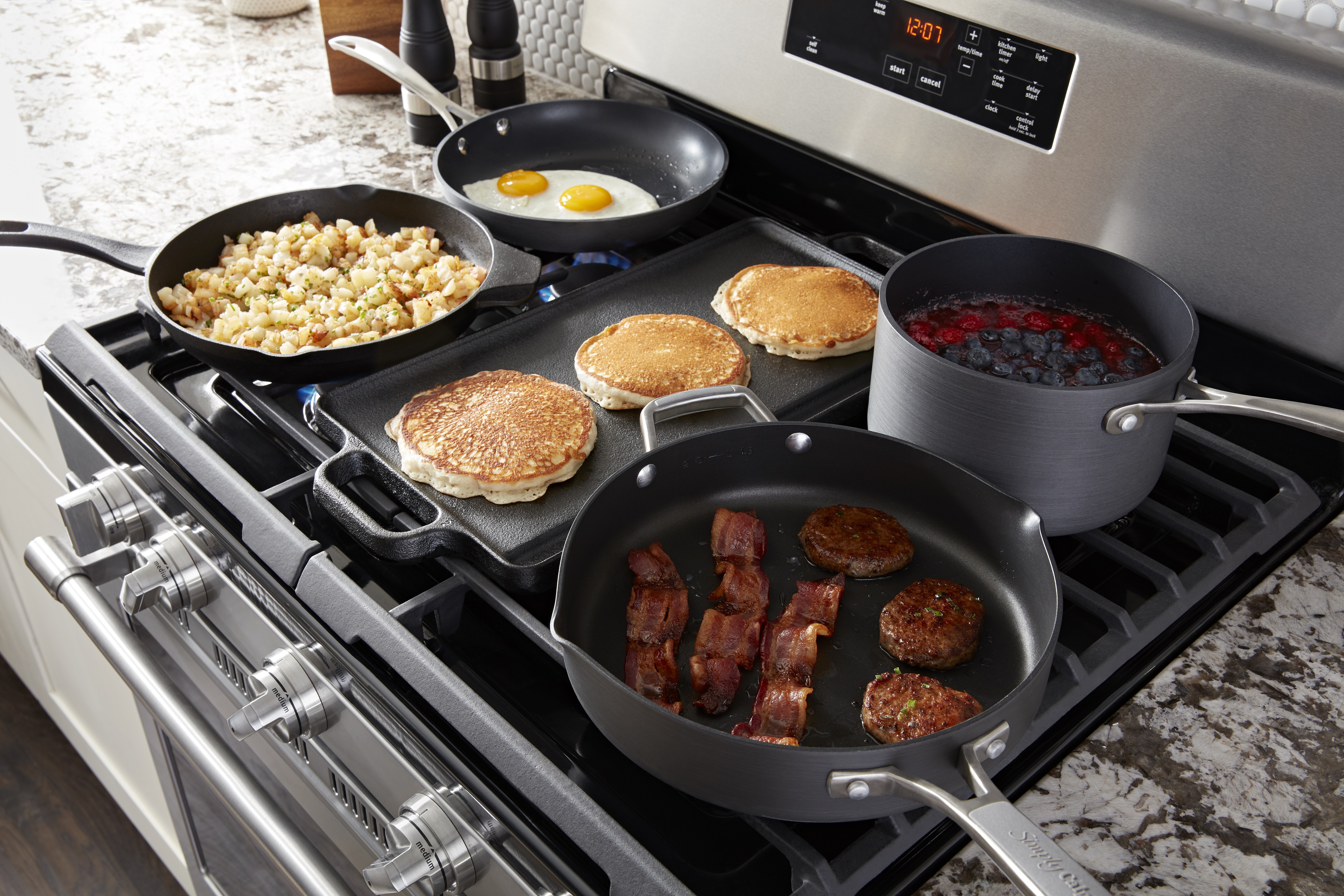 multiple pans with breakfast foods on Maytag gas range