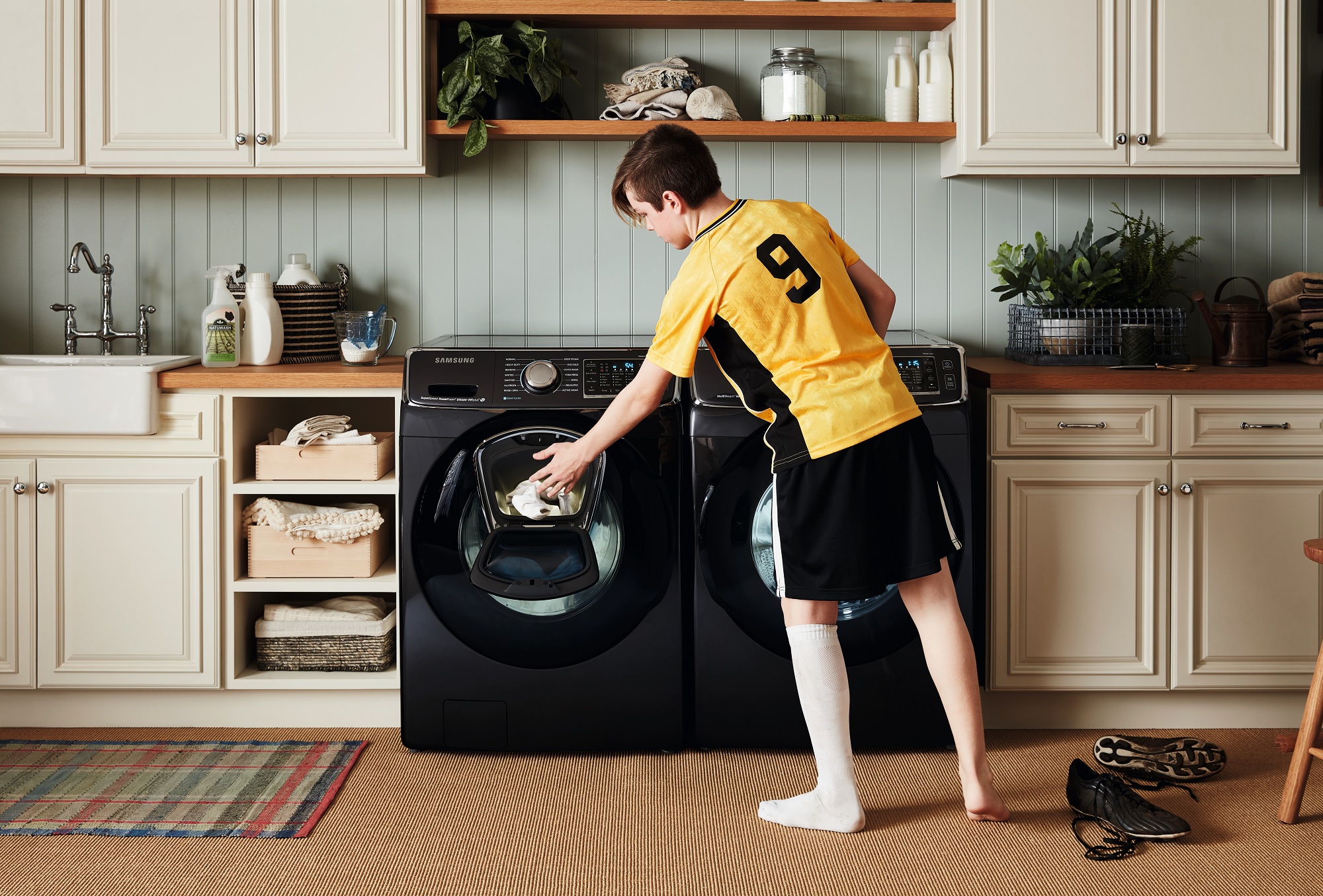 young boy in soccer uniform retrieves clothes from Samsung washer