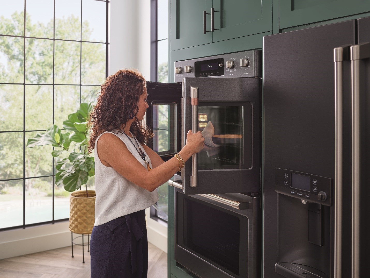 stylish woman opens French doors of Café black matte wall oven