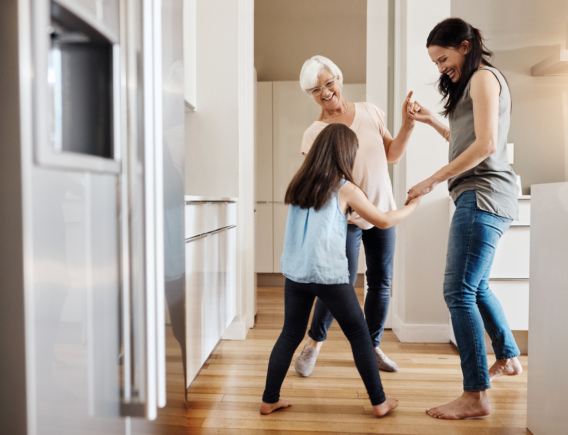 mother, daughter, and granddaughter dance joyfully in clean kitchen
