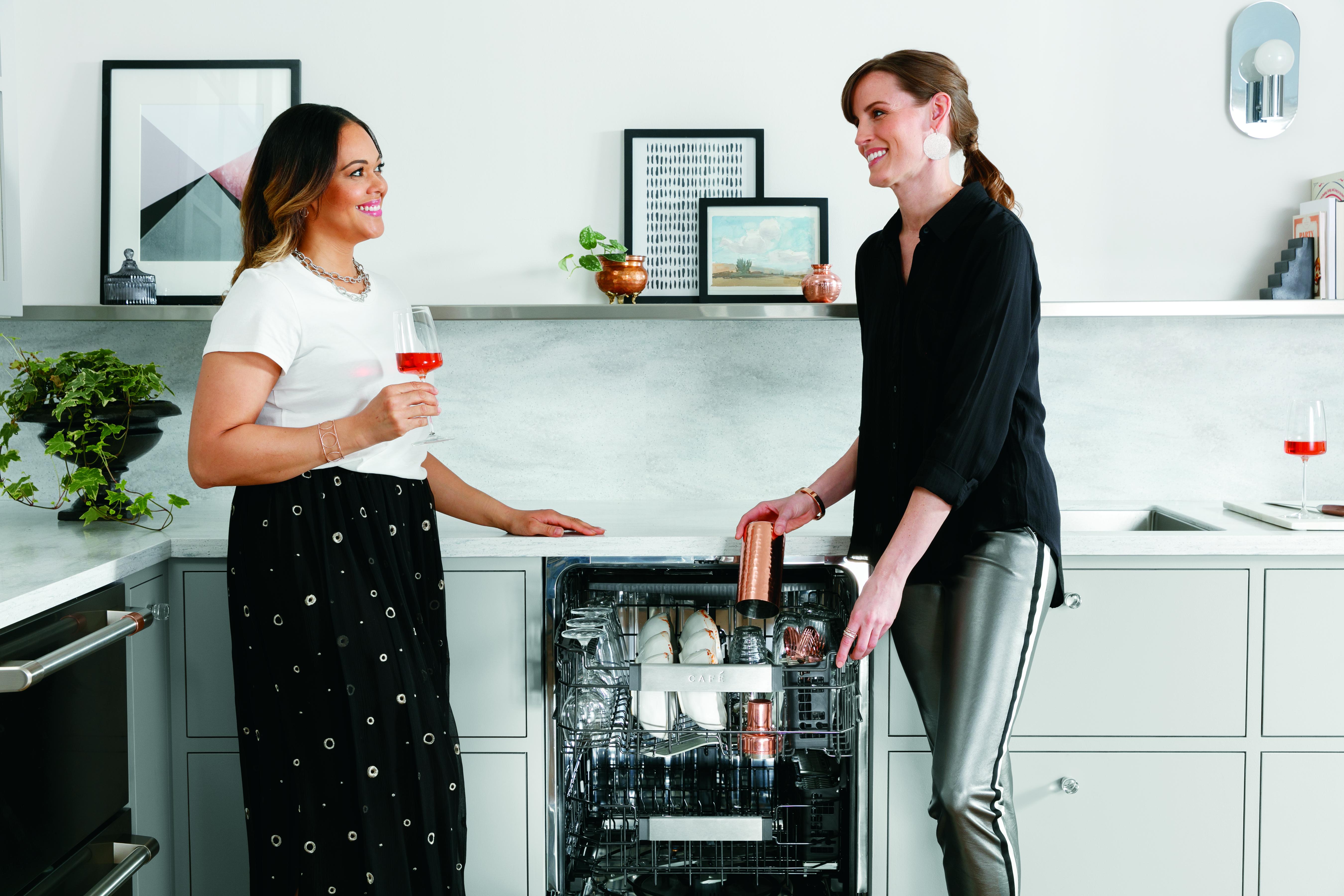 two women socialize as they unload a Café built-in dishwasher