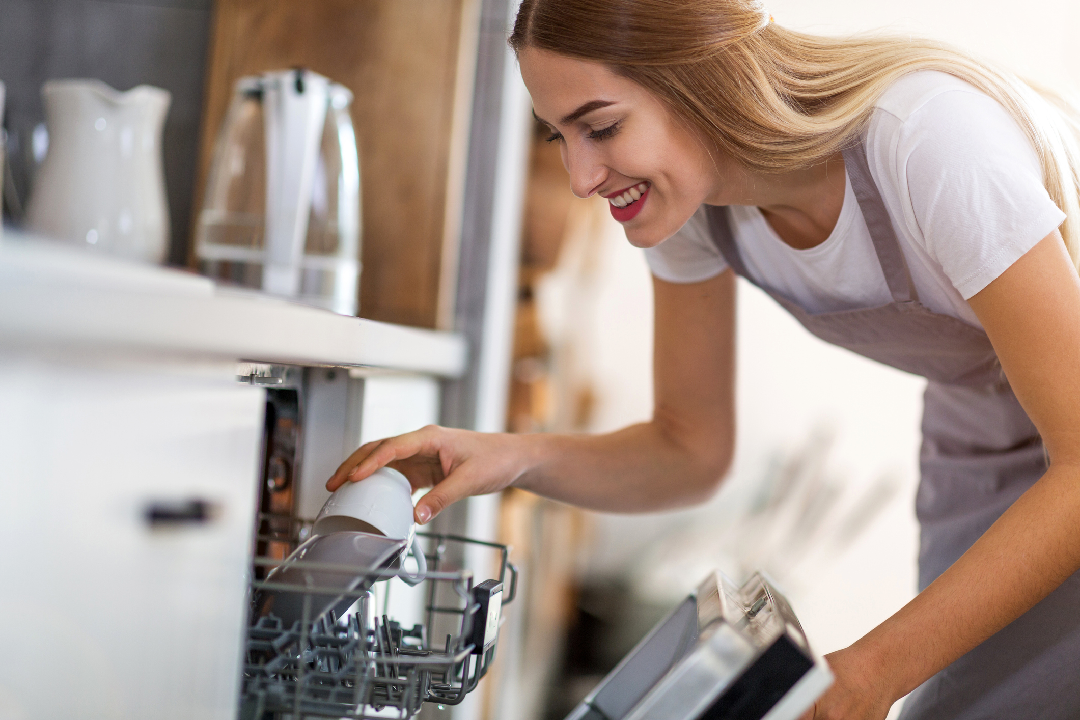 young woman loading the dishwasher