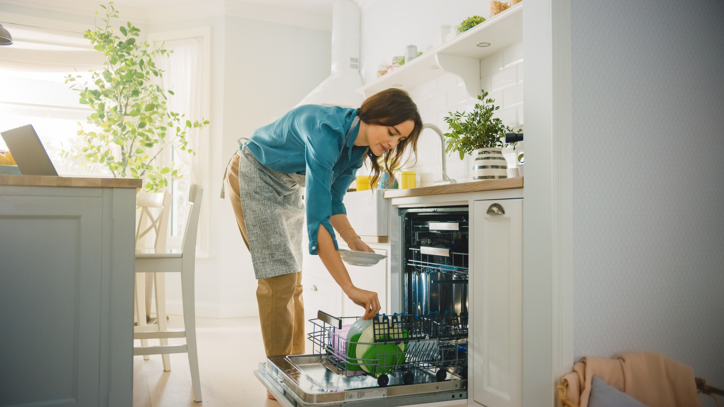 A woman places dishes in a dishwasher 