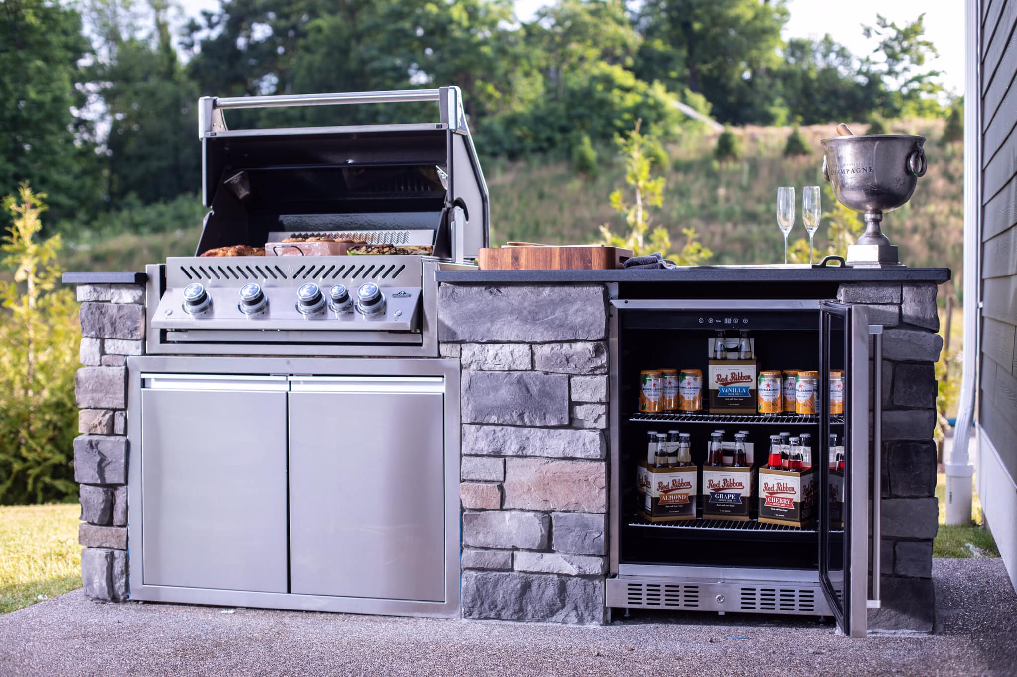 A built-in grill with a built-in beverage center installed into an outdoor kitchen island 