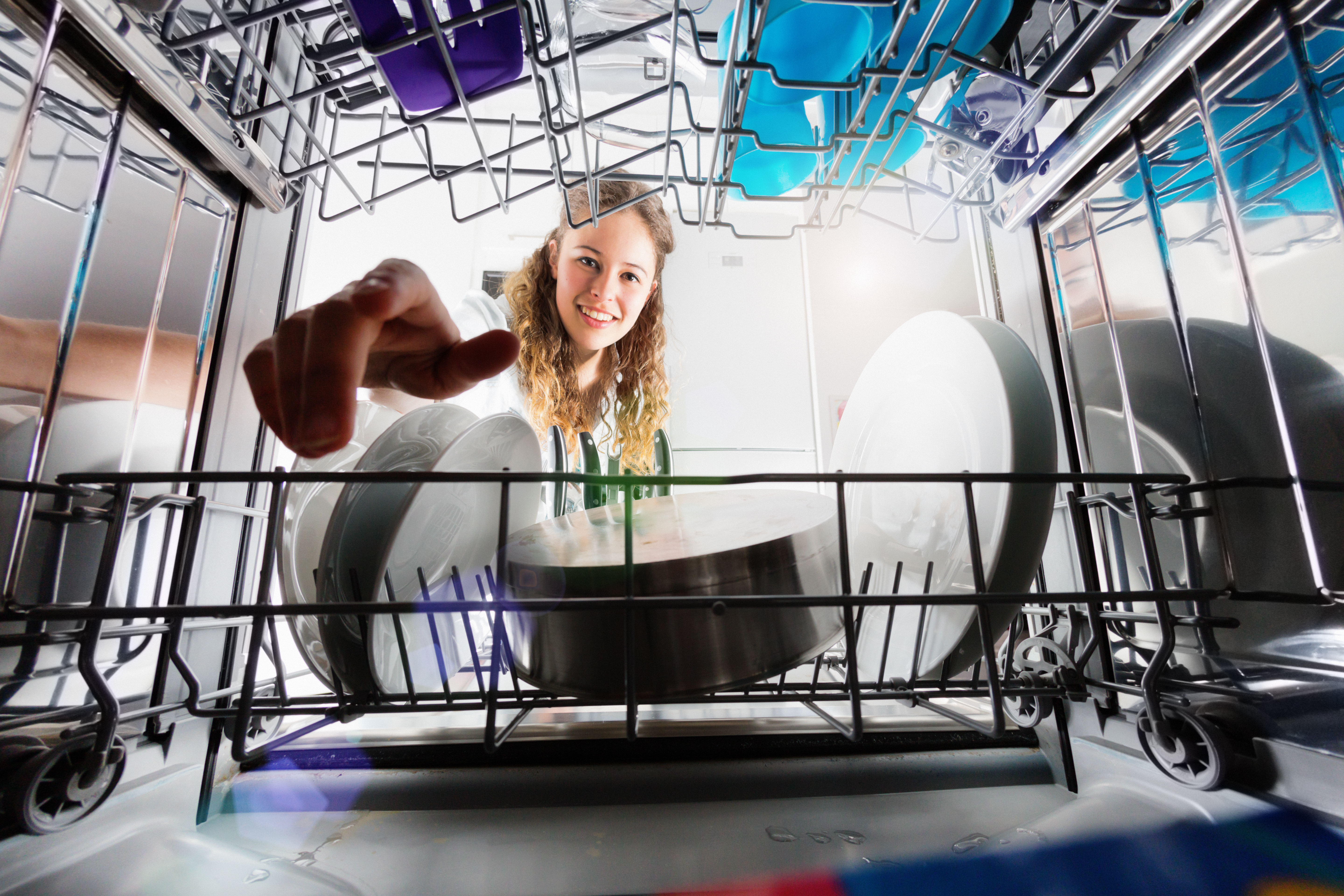 Woman smiling as she reaches into a dishwasher 