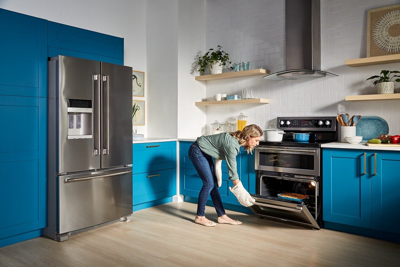 A woman taking out an entrée from a Maytag ymet8800fz 30” electric double oven range 