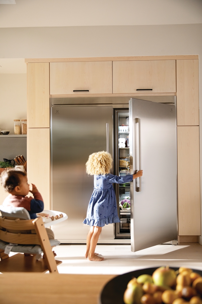 A young girl looking inside of a Frigidaire freezerless refrigerator 