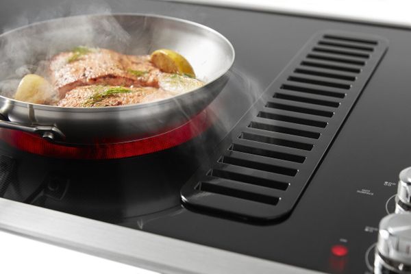 A closeup of salmon cooking atop a KitchenAid cooktop