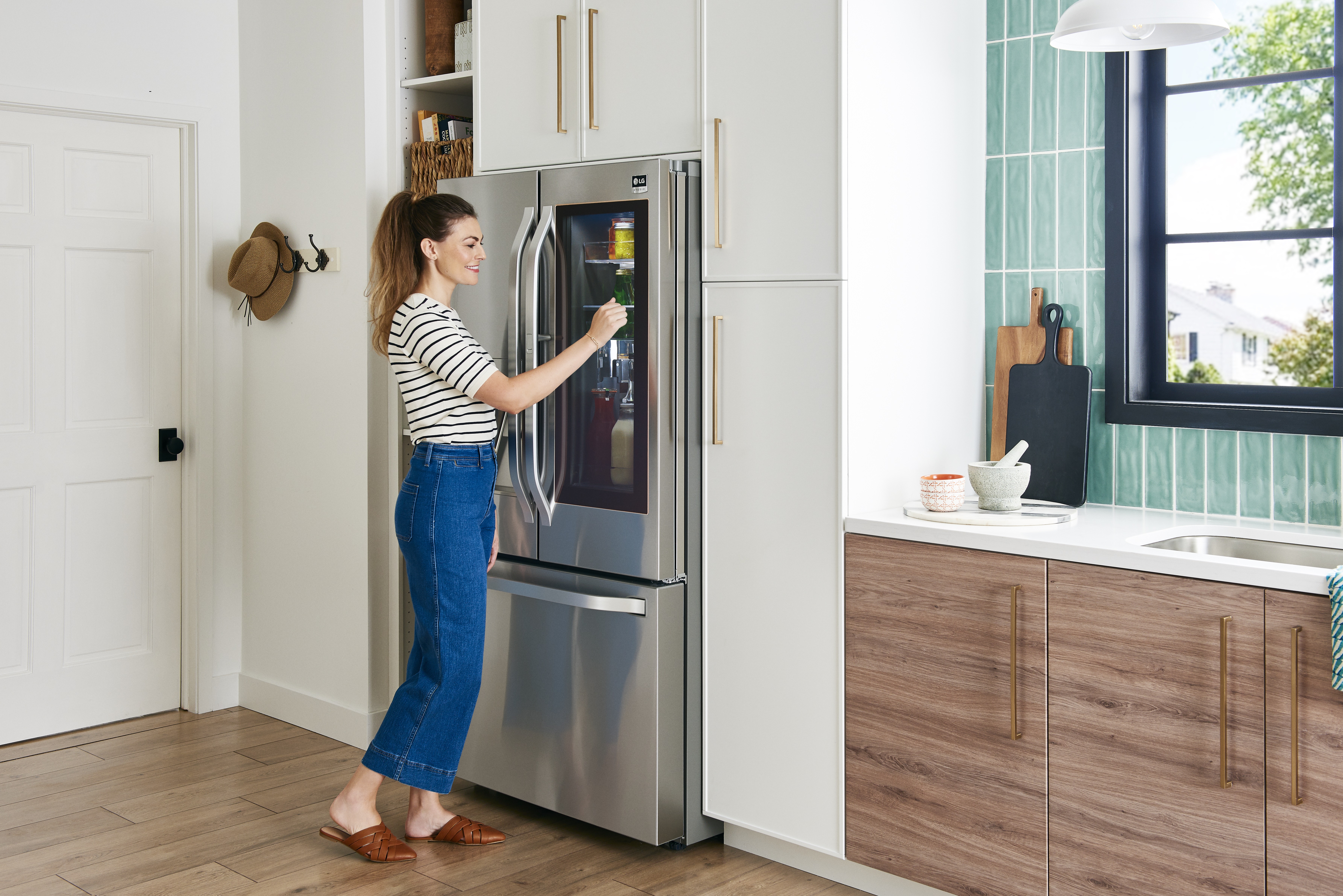 woman in striped shirt uses InstaView Door-in-Door feature on LG french door refrigerator