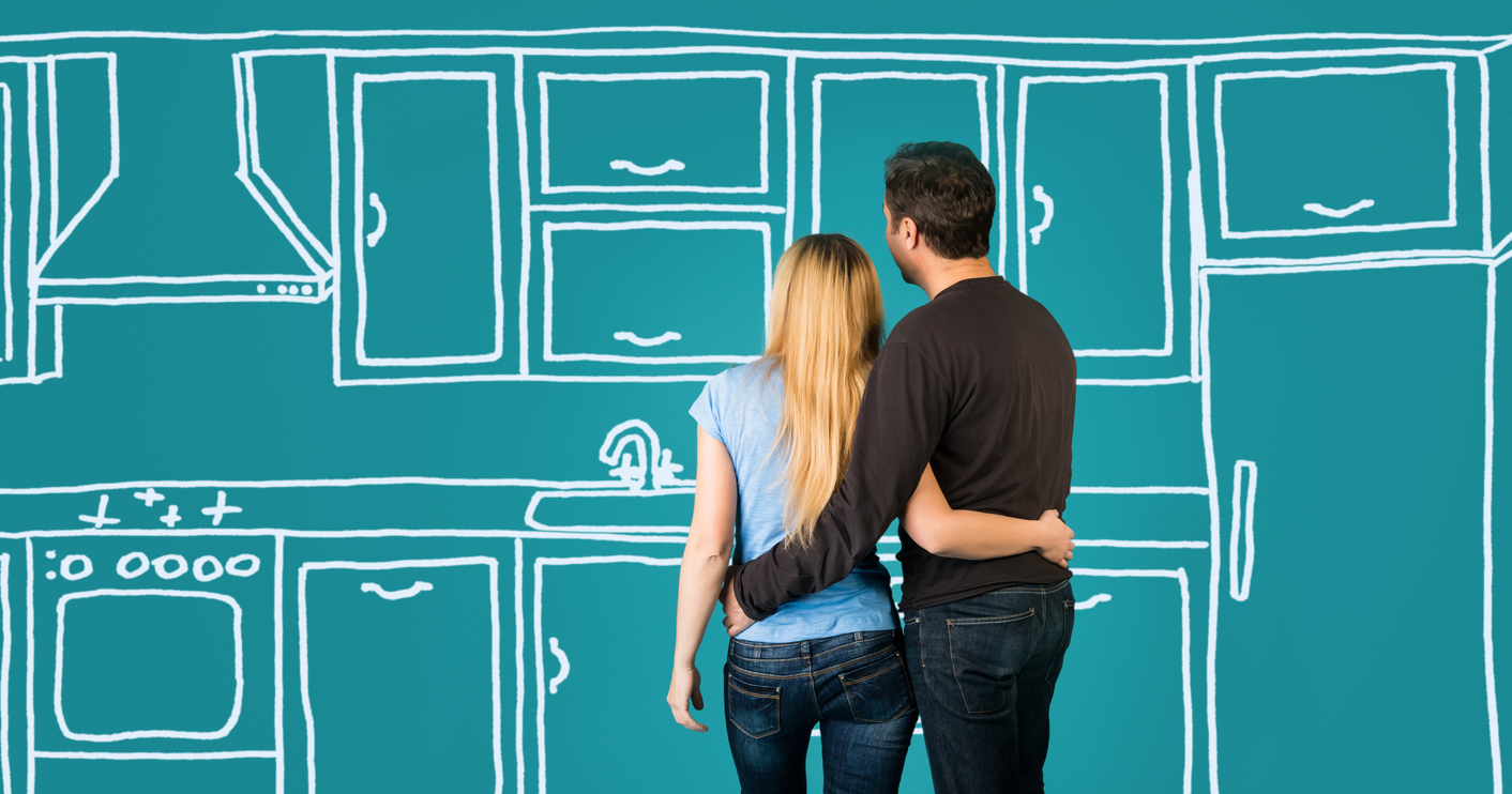 young male and female couple hug in front of teal kitchen design graphic