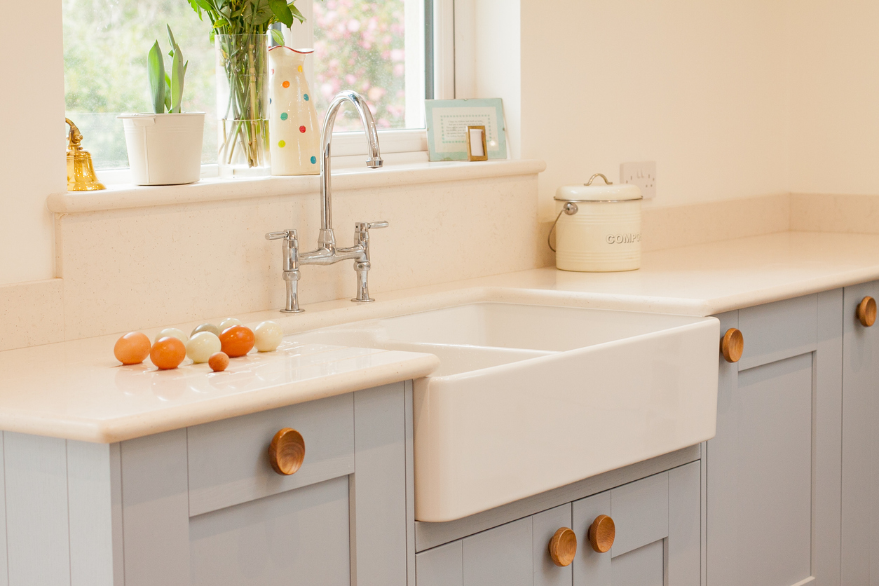 Farmhouse-style apron sink against grey cabinets and white countertop with eggs on it