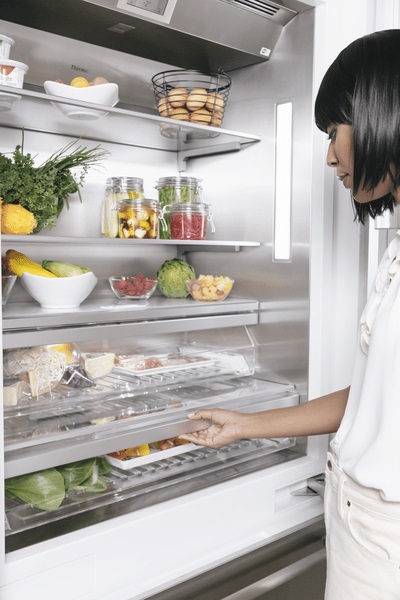 woman reaching into the thermador T36BT925NS refrigerator stocked with produce and foods