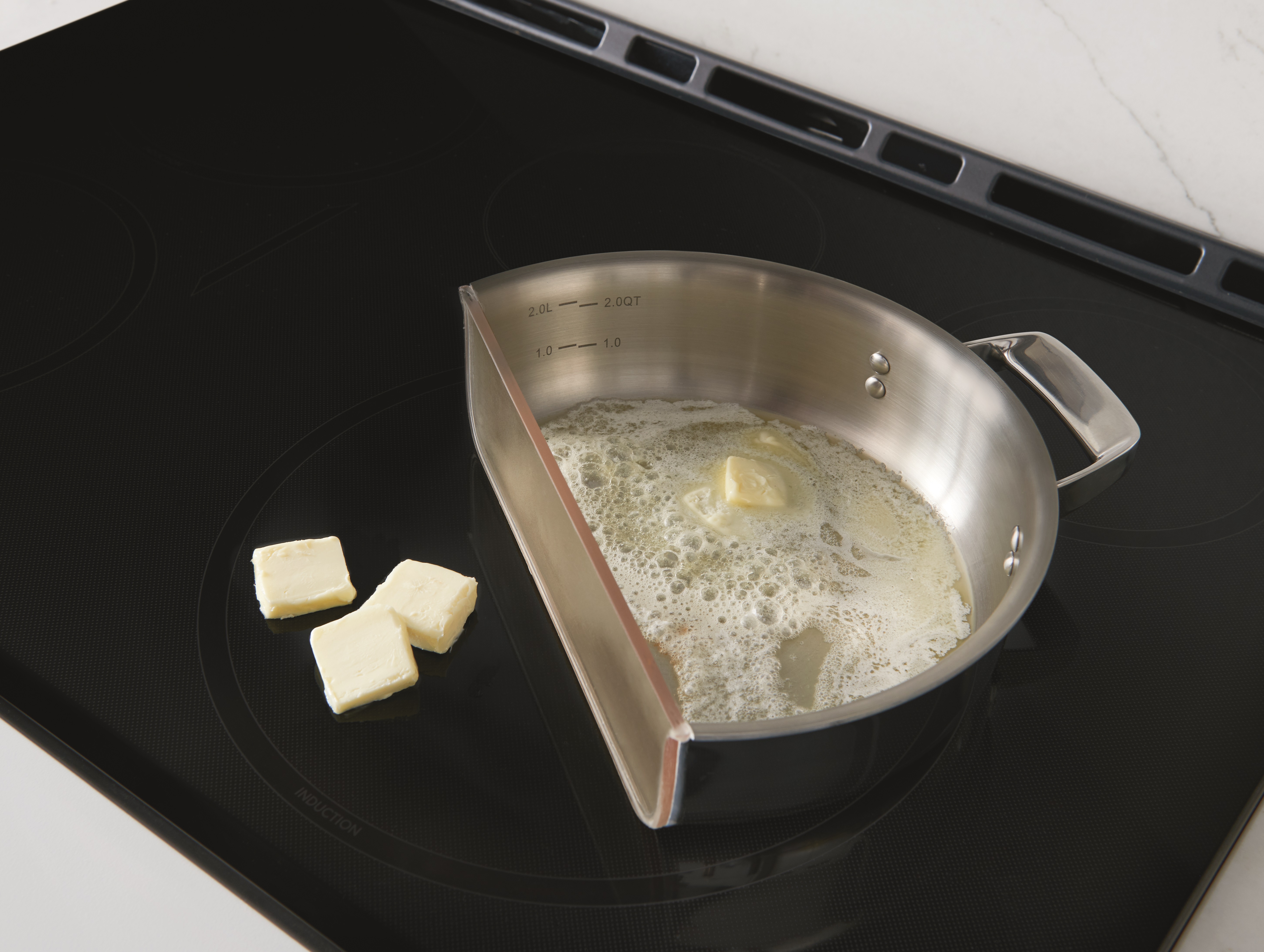 ge CHS950P4MW2 induction cooktop with bisected pan of melted butter next to unmelted butter