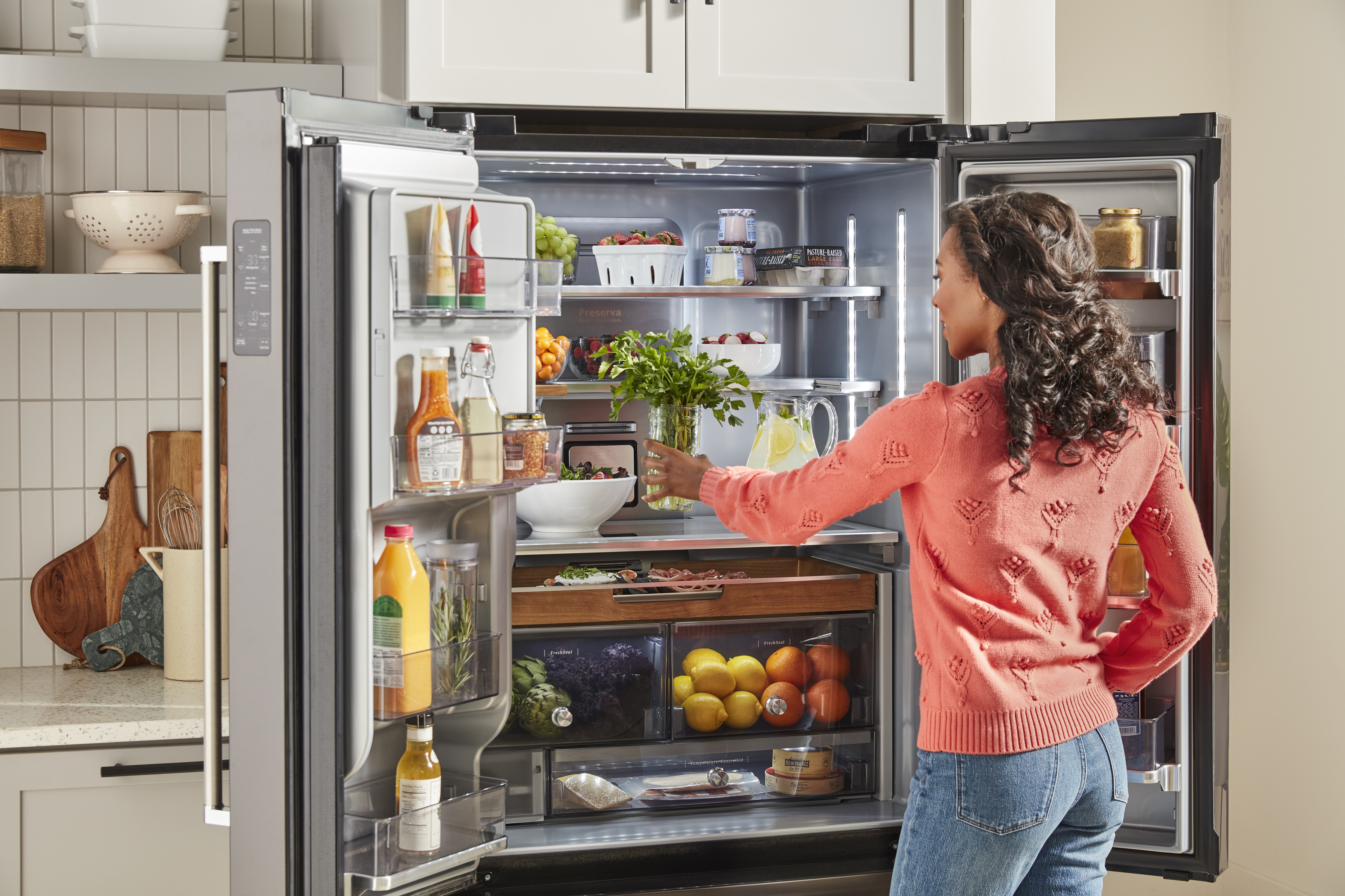 woman accesses inside of KitchenAid French door refrigerator