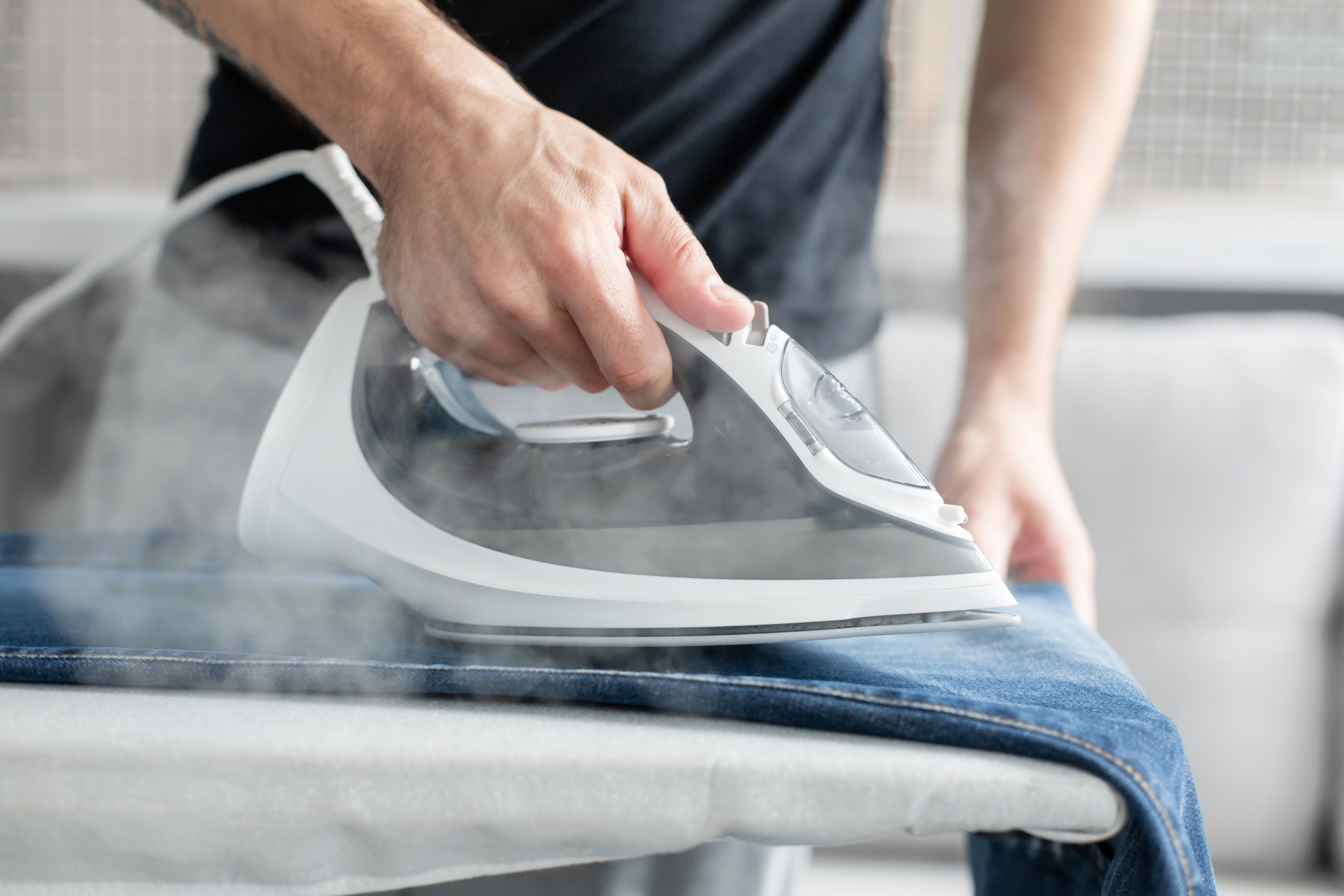 man ironing his blue jeans