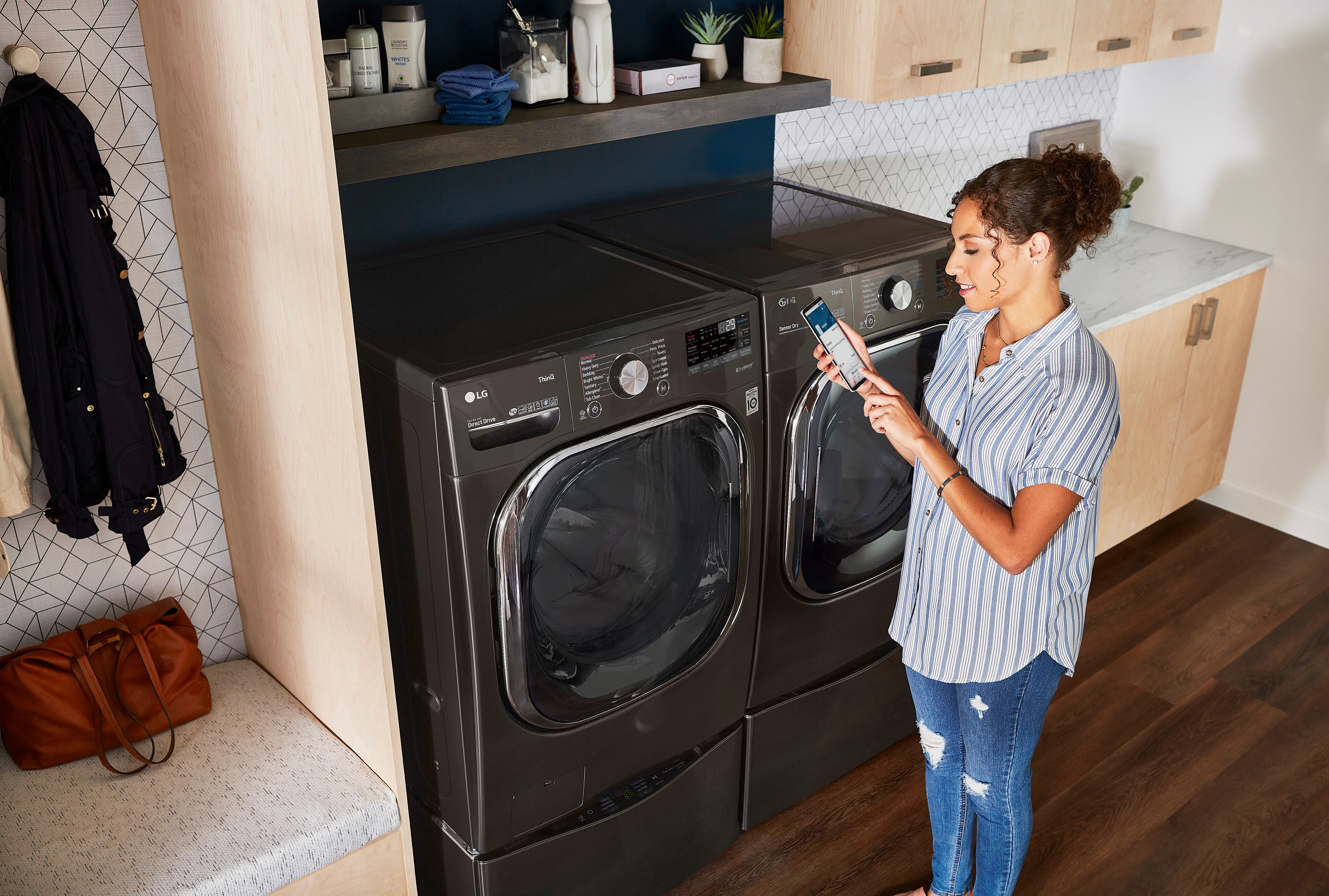 young woman uses ThinQ app to control her LG front load washer and dryer set