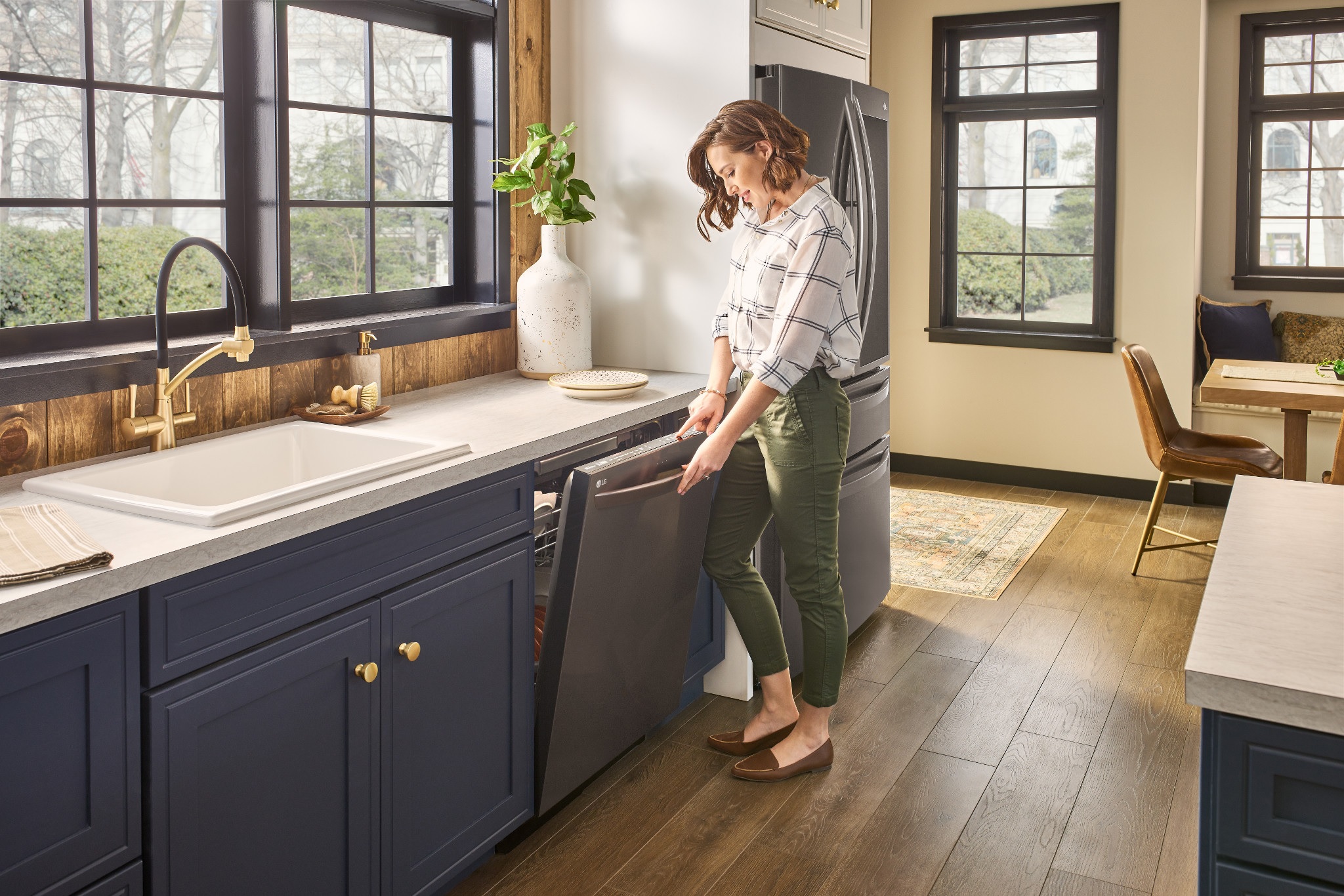 young woman opens LG stainless steel dishwasher to unload clean dishes