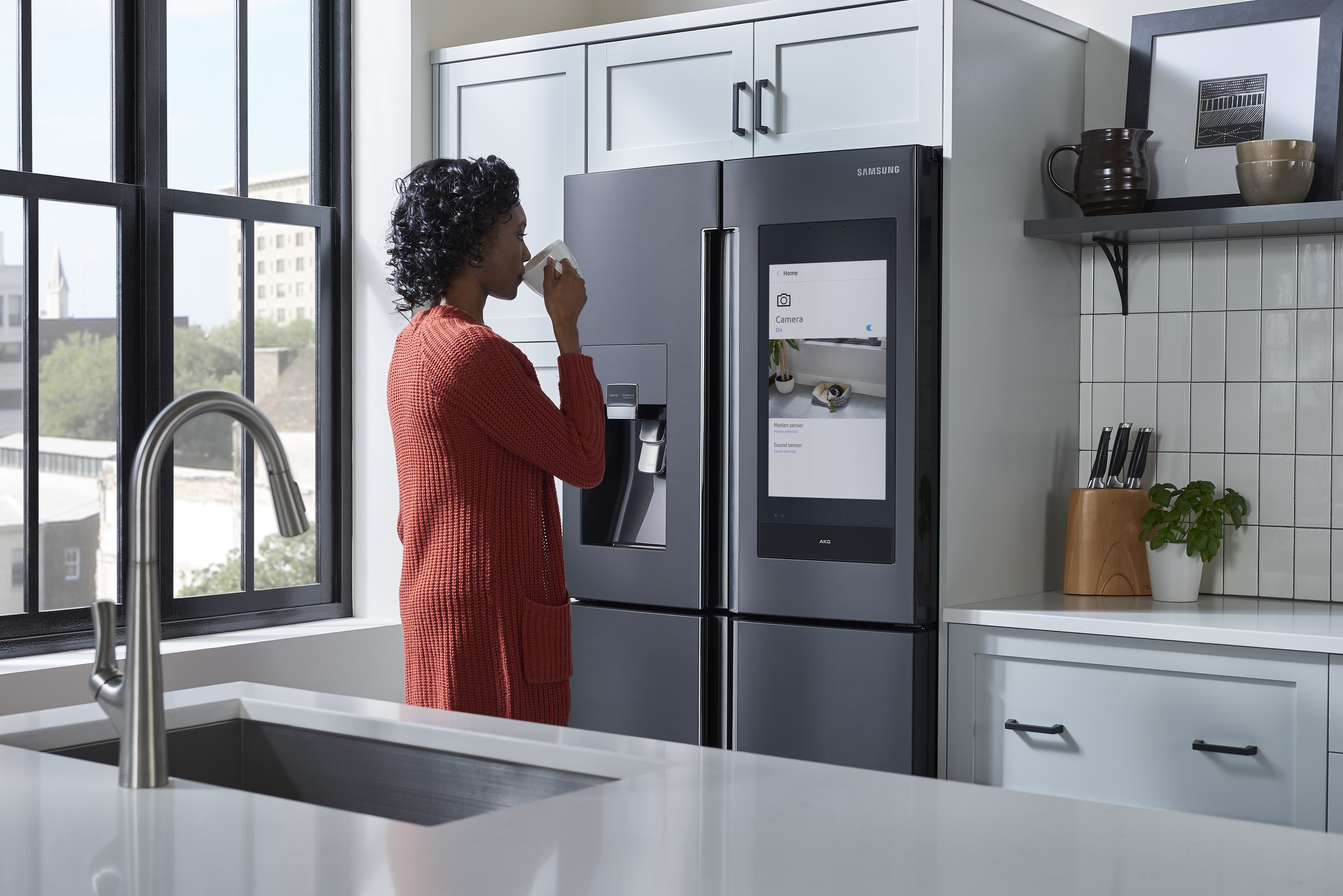 woman sips morning coffee while looking at Samsung Family Hub panel