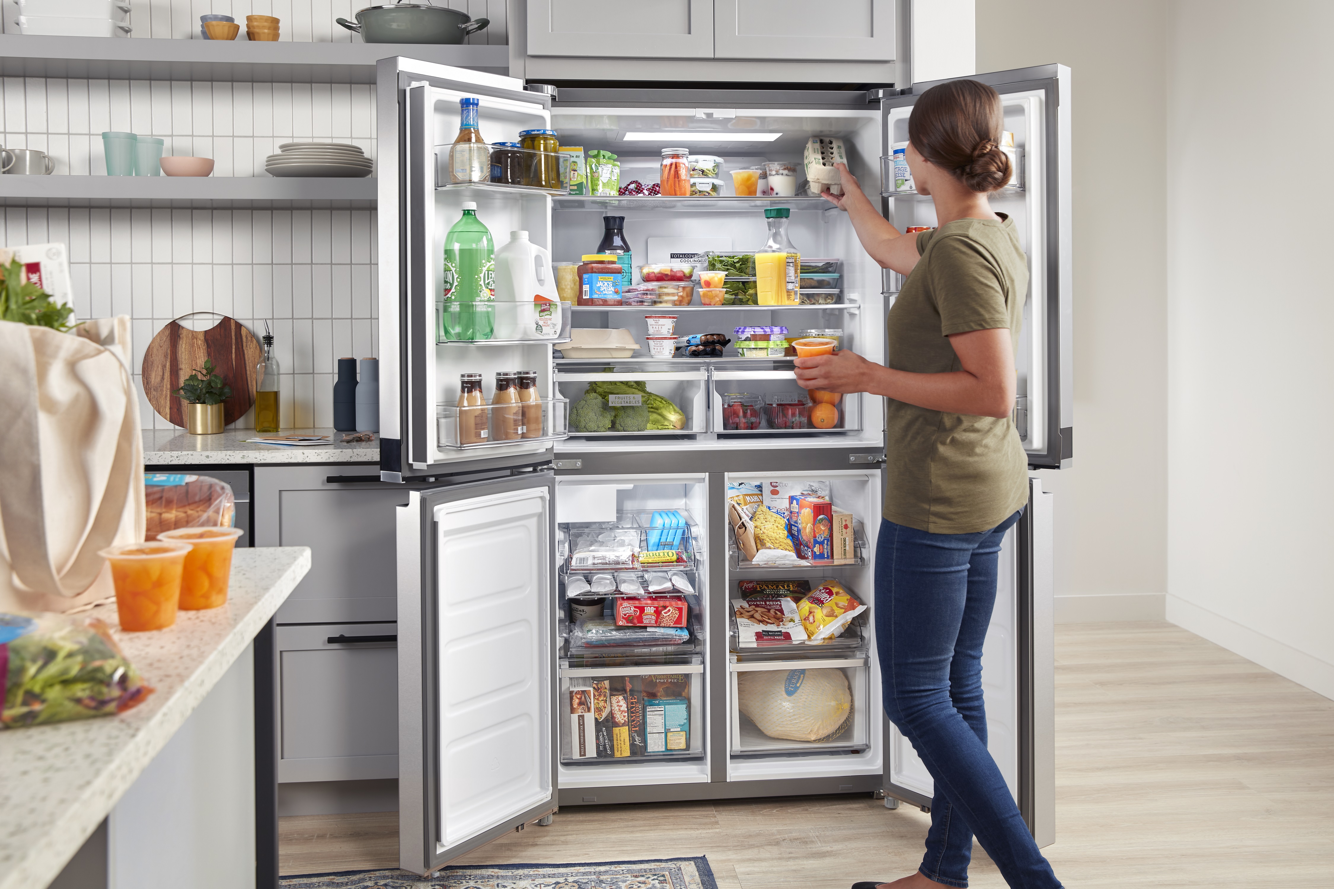 woman organizes four-door Whirlpool refrigerator
